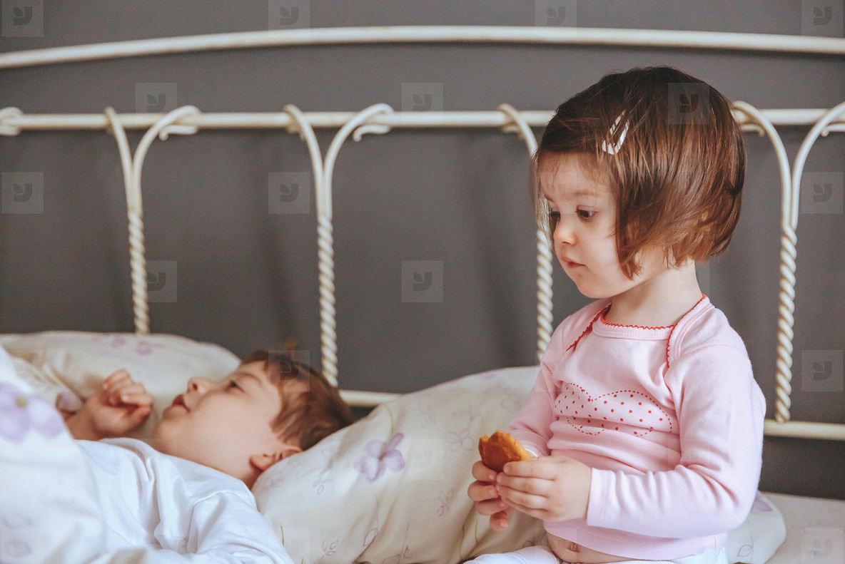 Little girl holding cookie sitting over the bed