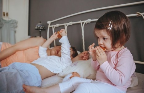 Relaxed little girl eating cookies over the bed