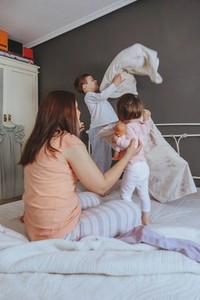 Relaxed mother and sons playing over the bed