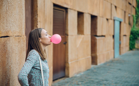 Young teenage girl blowing pink bubble gum
