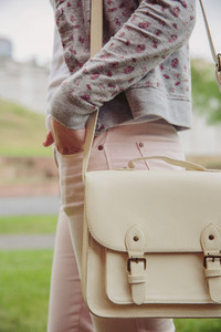 Young trendy woman holding white satchel bag outdoors