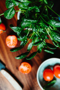 Lifestyle photo of cooking healthy eating with tomatoes and fresh spinach on a kitchen table