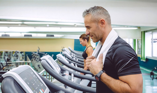 Man with towel in neck training over treadmill