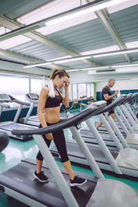 Woman drying with towel while training on treadmill