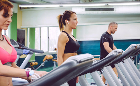 Woman with earphones training over a treadmill