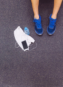 Man legs with sneakers  towel  water and smartphone in gym floor