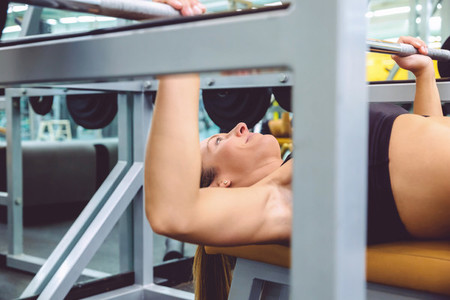 Woman with barbell on a bench press training