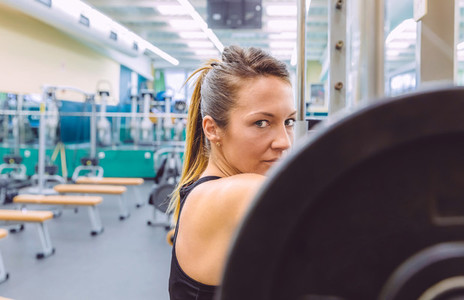 Woman resting after lifting barbell on muscular training