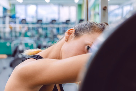 Woman resting tired after lifting barbell on muscular training