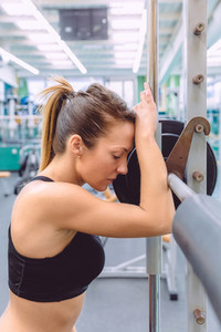 Woman resting tired after lifting barbell on muscular training