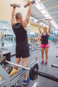 Man coach training to woman with dumbbells exercises