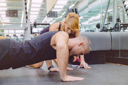 Personal trainer encouraging muscle man in push ups training