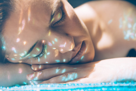 Woman face over hands with sparkles in skin