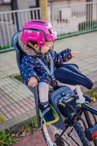 Little girl with helmet on head sitting in bike seat