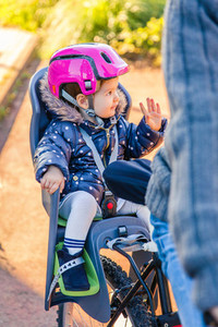 Little girl with helmet on head sitting in bike seat