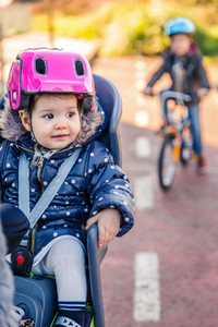 Lttle girl with helmet on head sitting in bike seat