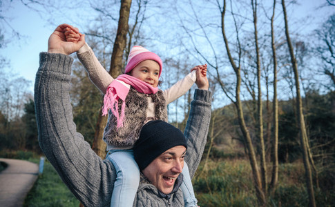Man giving piggyback ride to happy girl outdoors