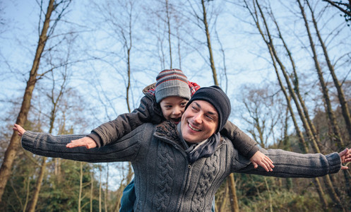 Man giving piggyback ride to happy kid in the forest
