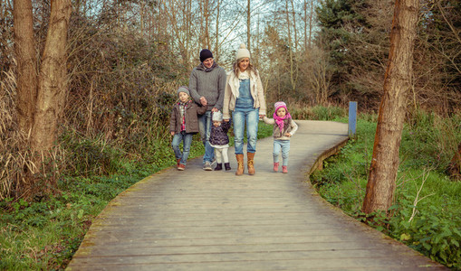 Happy family walking together holding hands in the forest