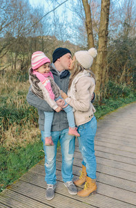 Couple with happy daughter kissing in the forest