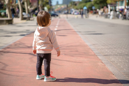 Little girl with sneakers standing over a city runway