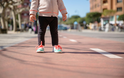 Little girl with sneakers and leggins standing over a city runway