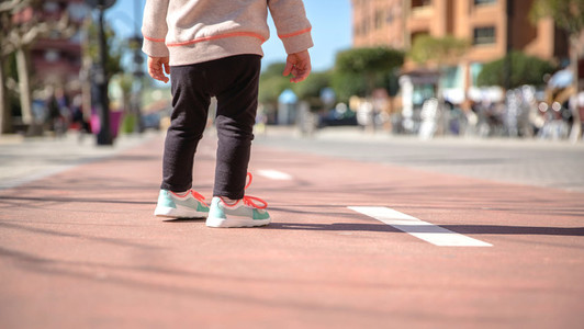 Little girl with sneakers and leggins standing over a city runway