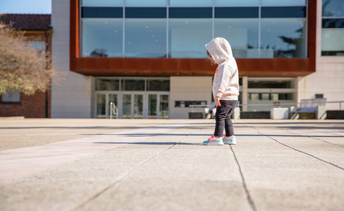 Little girl with hoodie looking her sneakers outdoors