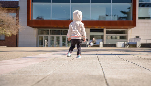 Little girl with sneakers and hoodie standing outdoors