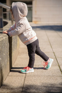 Little girl with sneakers and hoodie warming outdoors