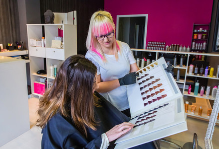 Woman looking with hairdresser a hair dye palette