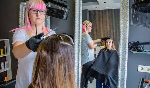 Woman looking in mirror to hairdresser combing hair