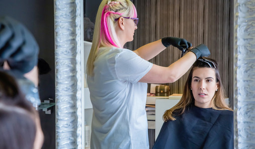 Woman looking in mirror to hairdresser combing hair