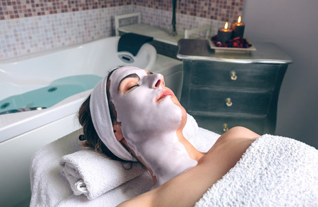 Relaxed woman lying with facial mask in spa