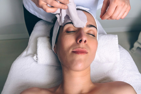 Woman lying while removing facial mask treatment in spa