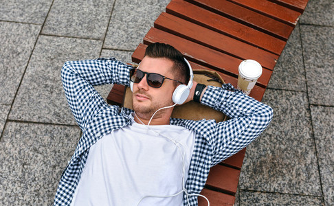 Man with headphones lying on a bench