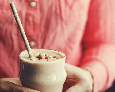 Hands holding a smoothie with banana  chia and almonds