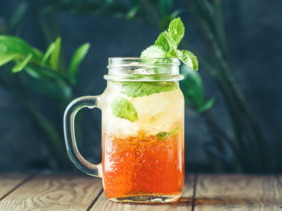 Ice black tea in a glass jar with fresh mint on a wooden table