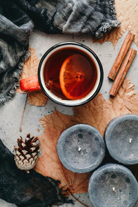 Autumn flat lay composition on a grey concrete background  Maple leaves  season tea with spices  black aromatic candles and warm scarf  Top view
