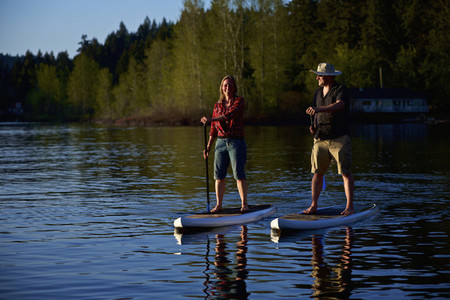Couple standup paddleboarding on sunny lake Shawnigan Lake