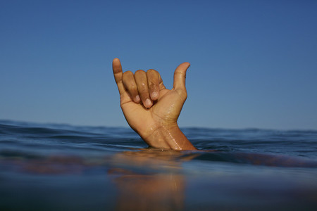 Close up male surfer gesturing shaka sign in ocean