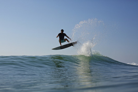 Male surfer jumping ocean wave