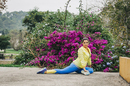Portrait fit female personal trainer exercising  stretching in park