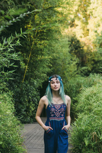Portrait young woman with blue hair on footpath in lush park