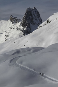 Snowshoers on sunny snowy mountain slope Switzerland