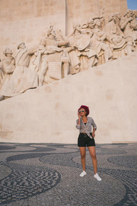 Stylish woman in sunglasses below Monument to the Discoveries  Lisbon  Portugal