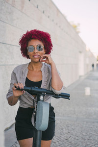 Portrait confident woman using shared public electric push scooter