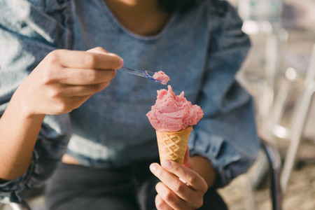 Close up woman eating pink ice cream cone