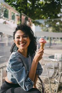 Happy woman eating ice cream cone on sunny cafe patio