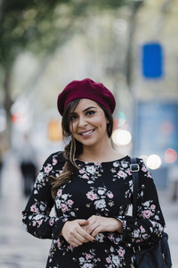 Portrait confident smiling young woman in beret and floral dress